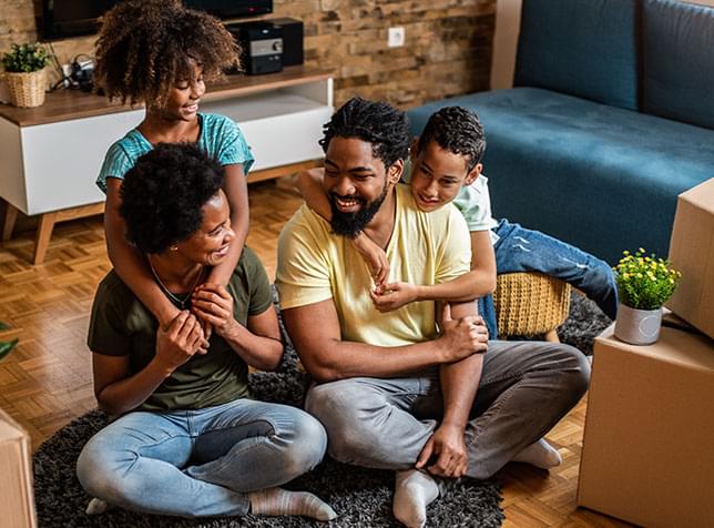 Family sitting on floor and smiling - link to The General Labs renters insurance page