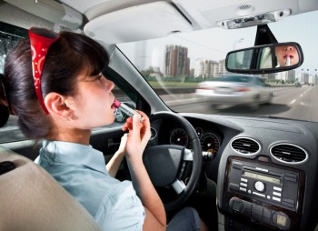 Woman putting on lipstick while driving