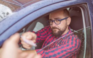 Man hands license to police officer - do speeding tickets affect car insurance
