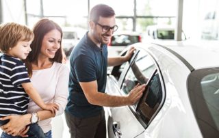 Happy couple with child buying a used car - shopping in a dealership