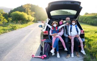 Family in car wearing masks going on a post-pandemic road trip.