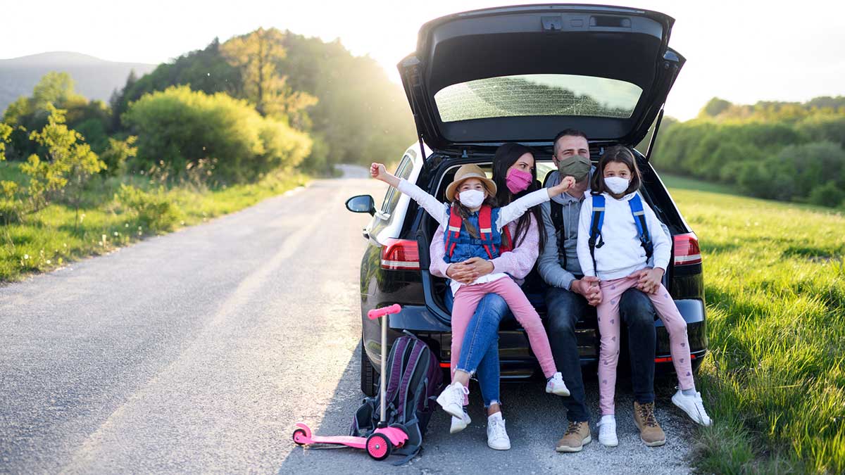 Family in car wearing masks going on a post-pandemic road trip.