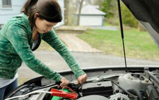 woman showing how to jump a car battery