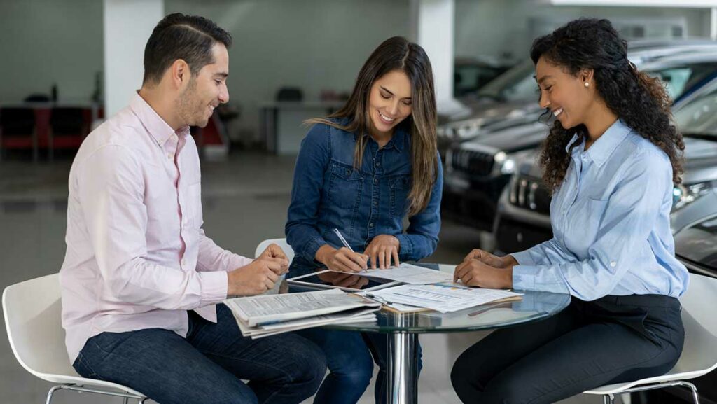 Couple Signing Document at a Car Dealership - Car Insurance on a Leased Car