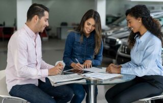 Couple Signing Document at a Car Dealership - Car Insurance on a Leased Car