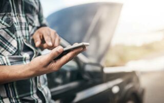 What does roadside assistance cover - man with phone and car hood up