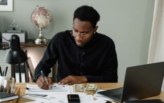 How to Budget for a Car - man with calculator and laptop making notes