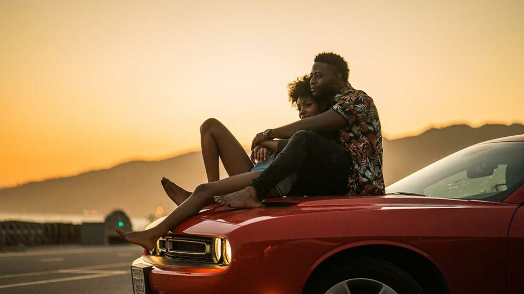 Photo of couple sitting on car hood on a Valentine's Road Trip