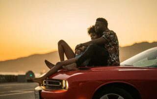 Photo of couple sitting on car hood on a Valentine's Road Trip