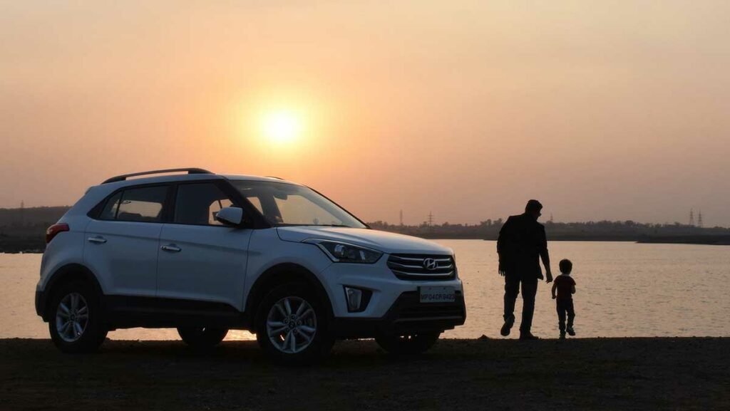 Safest car for families - father and son beside SUV at sunset