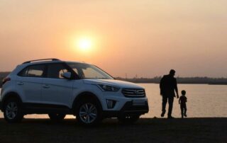 Safest car for families - father and son beside SUV at sunset