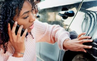 What to do when you get into a car accident - woman inspects damage to car