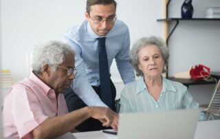 Older couple & business man looking at laptop - why do you need car insurance