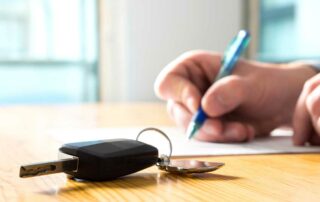 Man signing documents with car key on table - how to trade in your car
