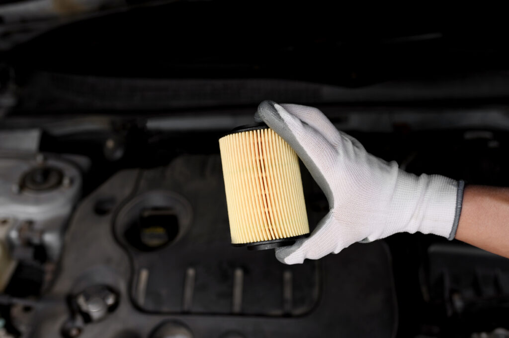 Replacing the oil filter on a car. A man's hand in gloves holds a new oil filter. Car repair concept