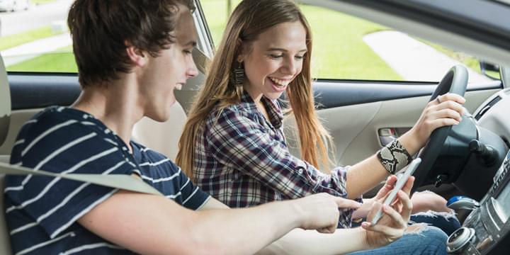 Young boy and girl looking at mobile phone while driving