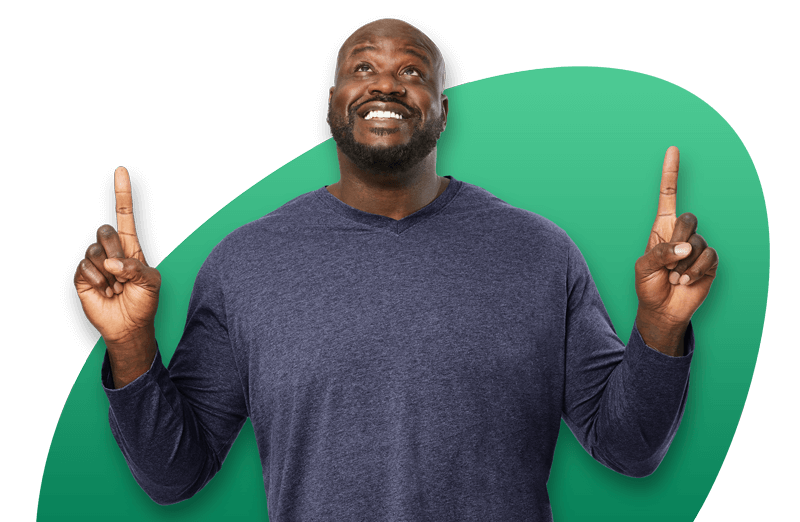 Shaquille O'Neal in grey shirt pointing up with both hands Shaquille O'Neal in grey shirt pointing up with both hands