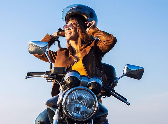 Person on motorcycle taking off their helmet - link to The General Motorcycle Insurance page