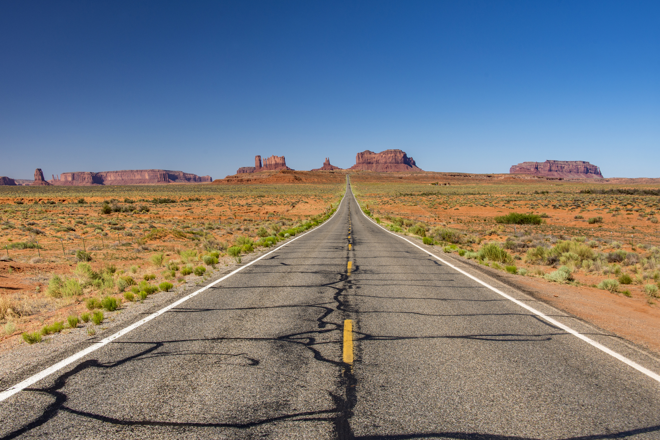Clear blue sky over a road in rough desert landscape with rock formations at Monument Valley in Arizona / along Route 66