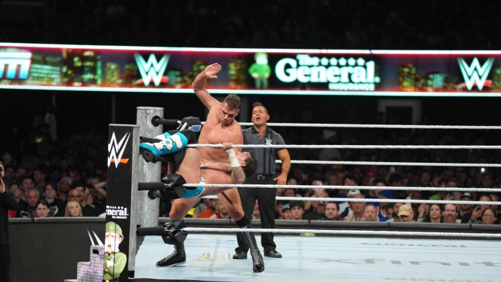 WWE SummerSlam match action in the ring with The General Auto Insurance branding, promoting a VIP WWE experience sweepstakes.